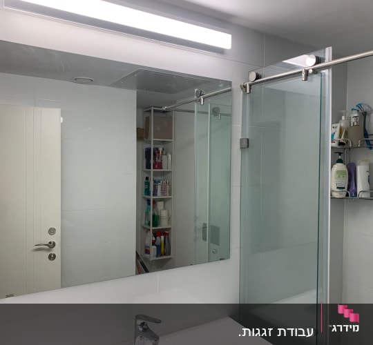 מראה גדולה ומקלחון זכוכית עם דלת הזזה בחדר רחצה